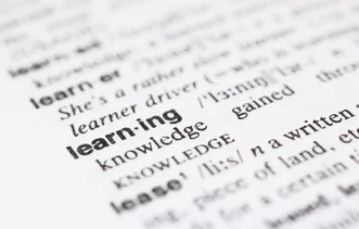 詞典頁面的微距照片，在周圍的定義文本中突出顯示粗體字「learning」。