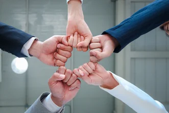正上方俯視圖顯示五名身穿西裝的人士將拳頭聚在一起，組成星形圓圈。