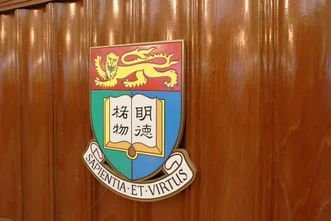 鑲嵌於光亮木牆上的香港大學校徽，展示中文校訓「明德格物」與拉丁文校訓「SAPIENTIA ET VIRTUS」。
