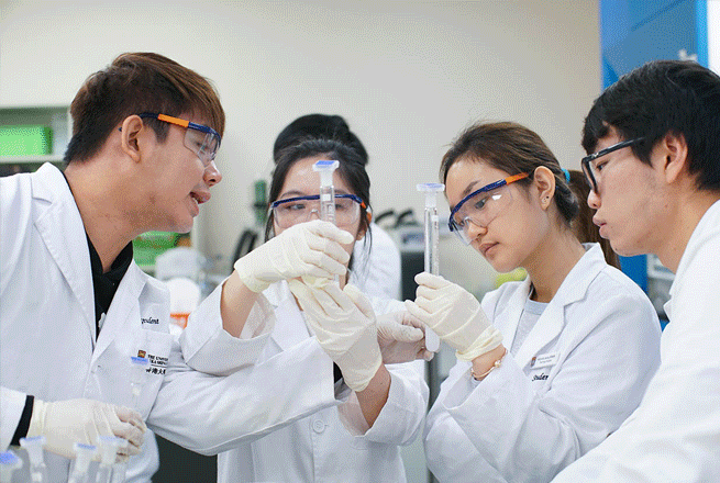 穿著實驗袍和防護眼鏡的香港大學學生在實驗室內觀察玻璃試管。