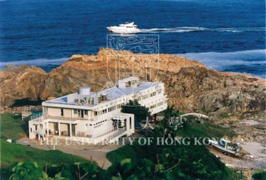 俯瞰圖：位於海岸岩石峭壁上的香港大學太古海洋科學研究所大樓，背景為深藍海洋及一艘航行的船隻。