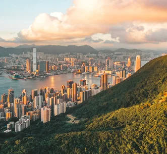 從太平山頂俯瞰維多利亞港及香港摩天大樓，整座城市沐浴在溫暖的陽光下。