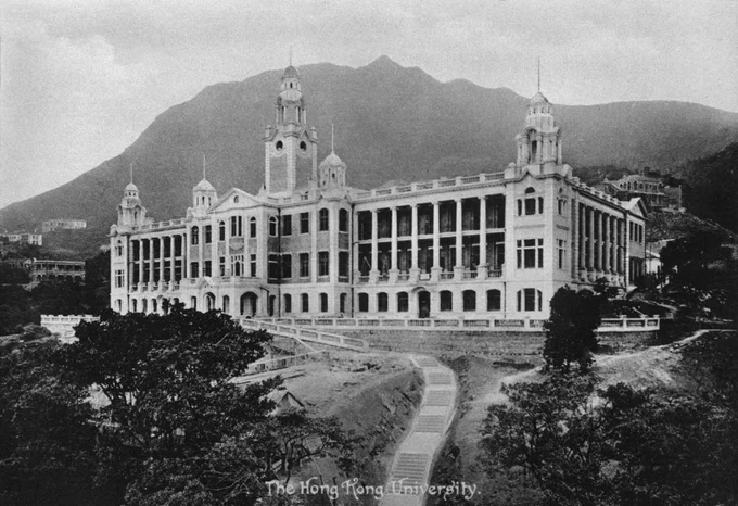 香港大學本部大樓的歷史黑白照片，中央設有鐘樓，背靠太平山，下方印有「The Hong Kong University」字樣。