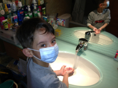 The child in Hong Kong shown in the photo wears a surgical face mask and practices hand washing.